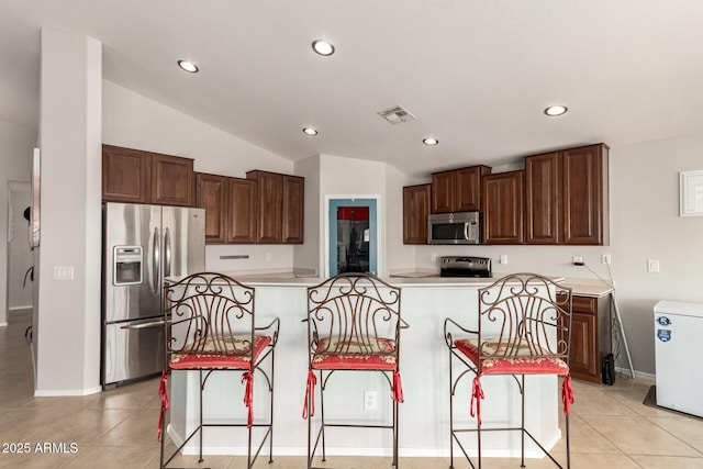 17562 W Desert Sage Dr, Goodyear, AZ 85338 - kitchen with appliances with stainless steel finishes, recessed lighting, light countertops, a breakfast bar, and lofted ceiling
