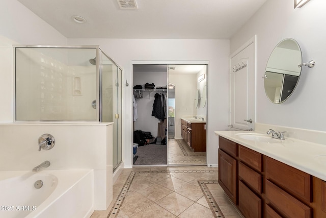 17562 W Desert Sage Dr, Goodyear, AZ 85338 - full bathroom featuring a shower stall, vanity, a garden tub, tile patterned flooring, and a walk in closet