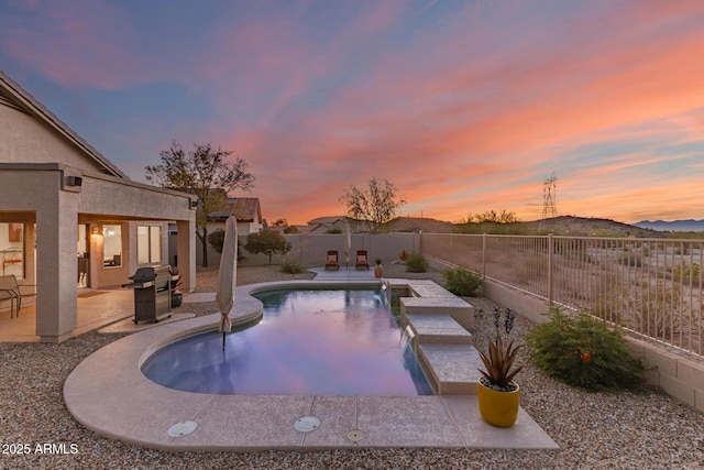17562 W Desert Sage Dr, Goodyear, AZ 85338 - pool at dusk featuring a patio, a fenced backyard, area for grilling, and a mountain view
