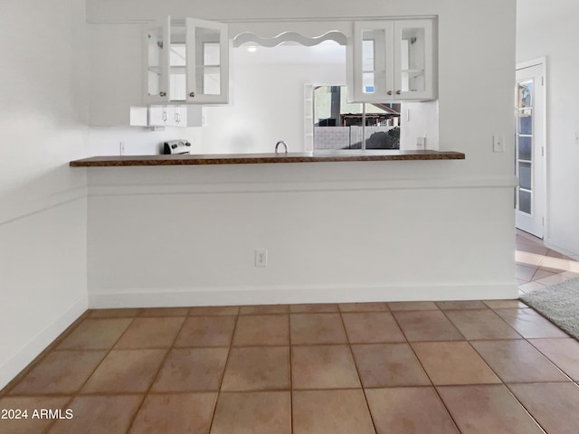 kitchen with tile patterned floors, white cabinets, and kitchen peninsula