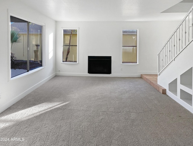 unfurnished living room with a wealth of natural light and carpet