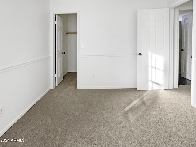 unfurnished bedroom with a walk in closet, a closet, and carpet