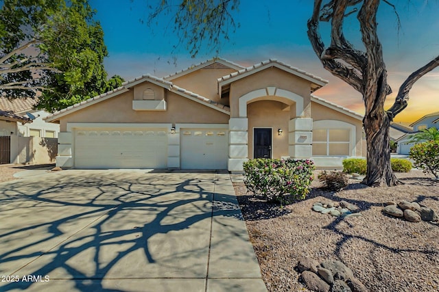 view of front facade with fence, stucco siding, concrete driveway, a garage, and a tile roof