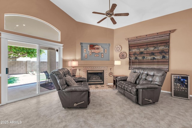 tiled living room featuring baseboards, beverage cooler, a tiled fireplace, high vaulted ceiling, and a ceiling fan