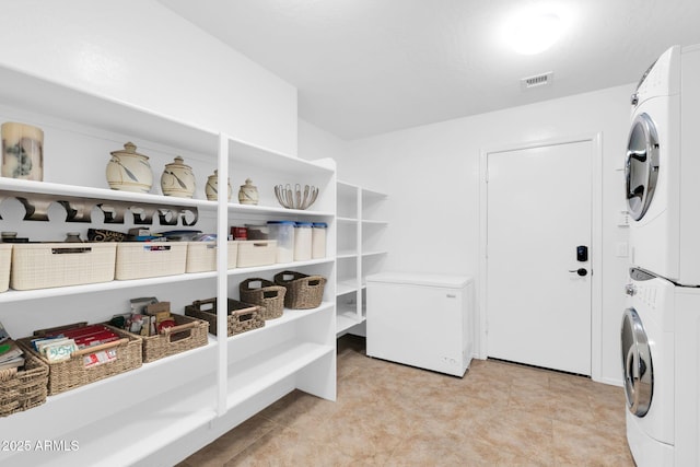 clothes washing area with laundry area, visible vents, and stacked washer and clothes dryer