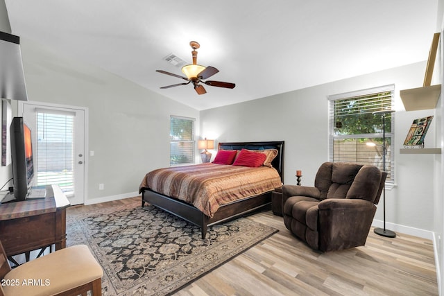 bedroom with light wood finished floors, baseboards, multiple windows, and vaulted ceiling