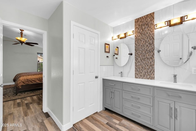 ensuite bathroom with a sink, wood finished floors, ensuite bath, tile walls, and double vanity