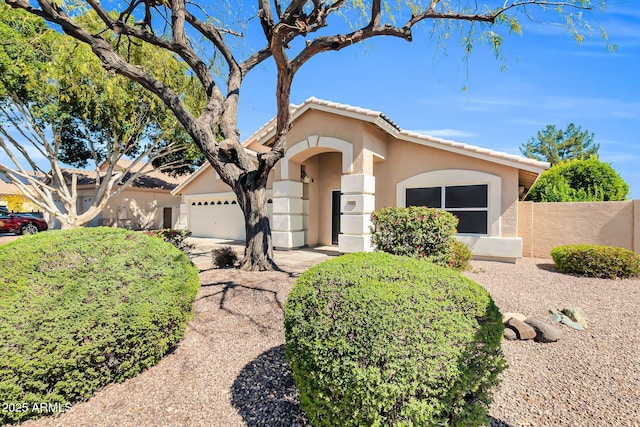 view of front of house with a tiled roof, stucco siding, a garage, and fence