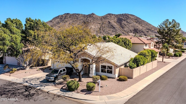 view of front of home with stucco siding, a mountain view, a tile roof, and fence