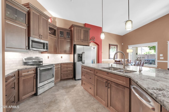 kitchen with lofted ceiling, a sink, decorative backsplash, appliances with stainless steel finishes, and decorative light fixtures