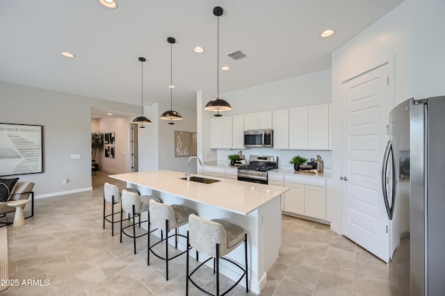 kitchen featuring pendant lighting, sink, appliances with stainless steel finishes, a kitchen island with sink, and white cabinets