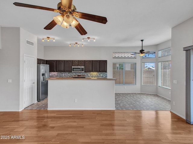 11547 W King Snake Ct, Surprise, AZ 85378 - kitchen with stainless steel appliances, ceiling fan, dark brown cabinetry, light wood-type flooring, and tasteful backsplash