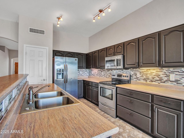 11547 W King Snake Ct, Surprise, AZ 85378 - kitchen with appliances with stainless steel finishes, a sink, tasteful backsplash, light countertops, and dark brown cabinetry