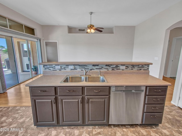 11547 W King Snake Ct, Surprise, AZ 85378 - kitchen with stainless steel dishwasher, a sink, a ceiling fan, arched walkways, and tasteful backsplash