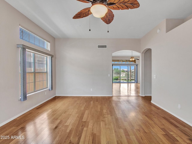11547 W King Snake Ct, Surprise, AZ 85378 - unfurnished room featuring a ceiling fan, arched walkways, light wood-style flooring, and baseboards