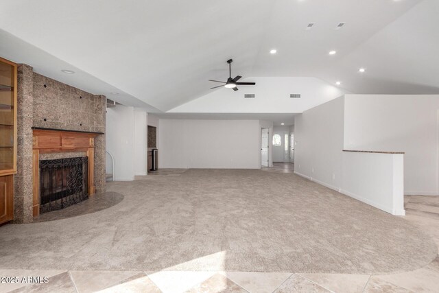 unfurnished living room featuring light carpet, a tiled fireplace, lofted ceiling, and ceiling fan