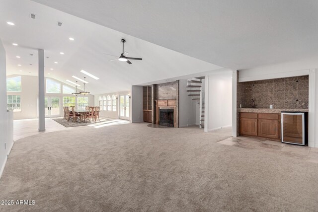 unfurnished living room with ceiling fan, high vaulted ceiling, and light carpet