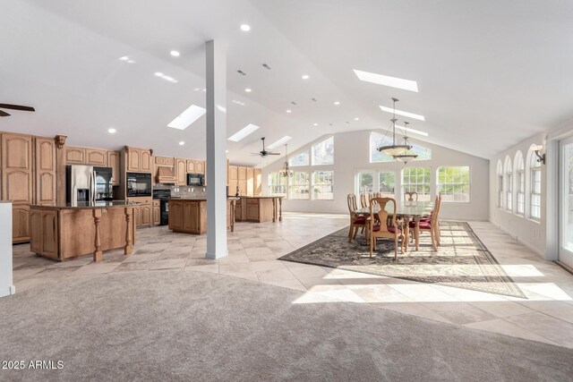 carpeted dining area with a skylight, high vaulted ceiling, and ceiling fan