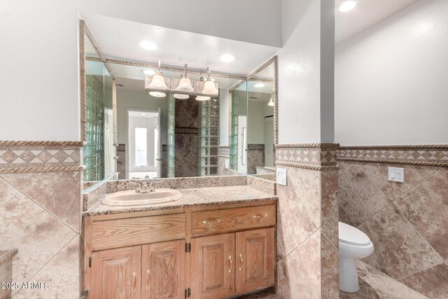 bathroom with vanity, toilet, and tile walls