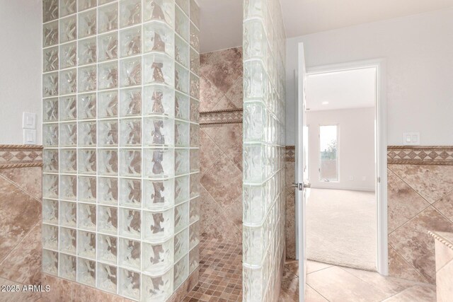 bathroom featuring tile patterned flooring, tile walls, and a tile shower