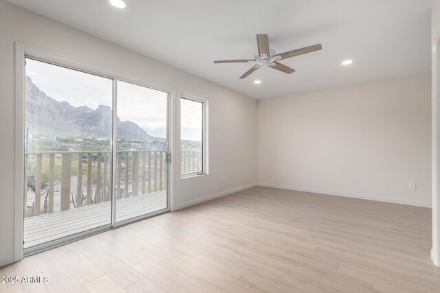 empty room featuring ceiling fan, a mountain view, and light hardwood / wood-style floors