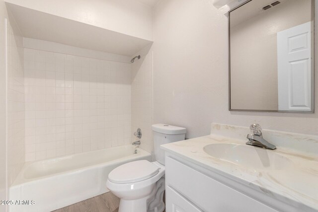 full bathroom with vanity, hardwood / wood-style floors, tiled shower / bath combo, and toilet