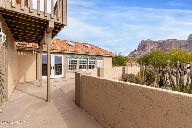 view of patio with a balcony, a mountain view, and french doors