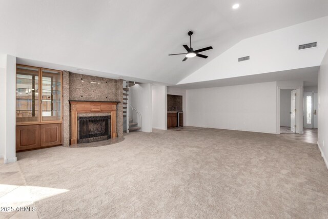 unfurnished living room with ceiling fan, light colored carpet, a premium fireplace, and high vaulted ceiling