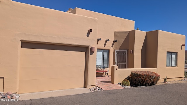 pueblo-style home featuring a garage and stucco siding
