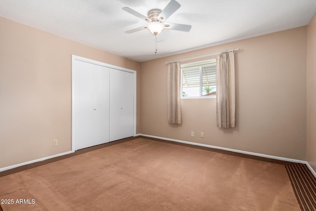 unfurnished bedroom with a textured ceiling, baseboards, a closet, and carpet flooring