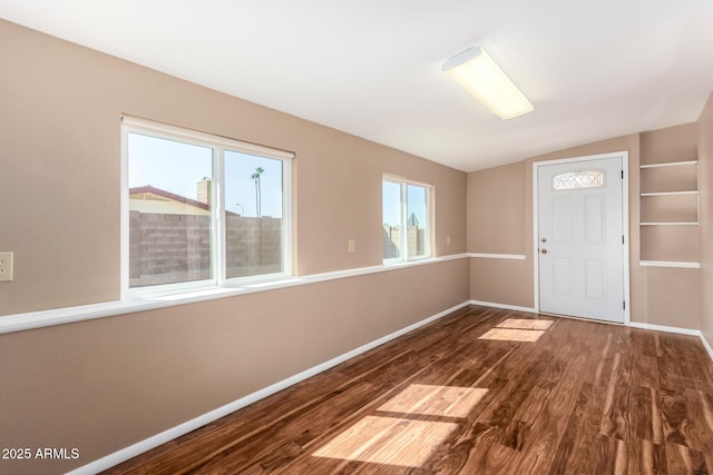 interior space featuring vaulted ceiling, wood finished floors, and baseboards