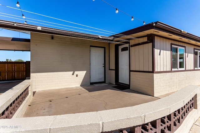 view of exterior entry featuring brick siding and fence