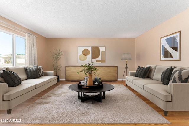 living area with baseboards, a textured ceiling, and light wood finished floors