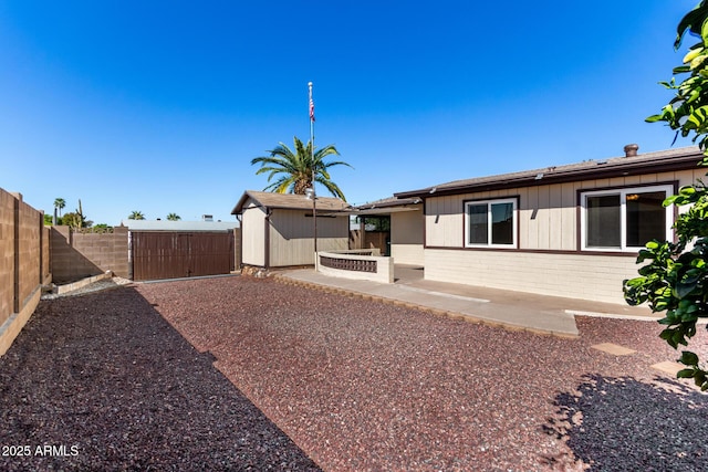 back of property featuring a patio, a fenced backyard, a storage shed, brick siding, and an outdoor structure