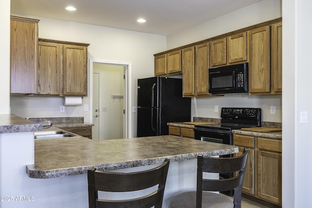 kitchen featuring kitchen peninsula, sink, a breakfast bar area, and black appliances