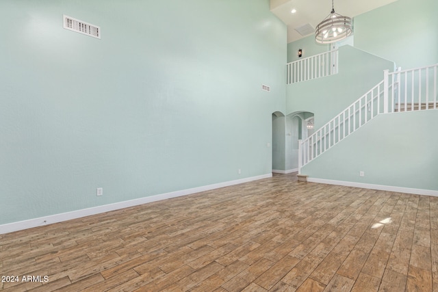 unfurnished living room featuring hardwood / wood-style flooring and a high ceiling