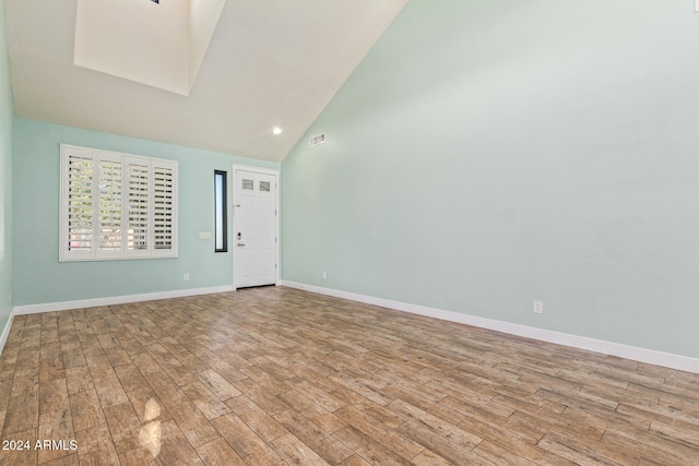 unfurnished room with high vaulted ceiling and light hardwood / wood-style flooring