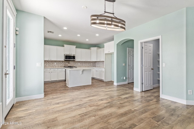 kitchen with decorative backsplash, light hardwood / wood-style flooring, a center island, pendant lighting, and white cabinets