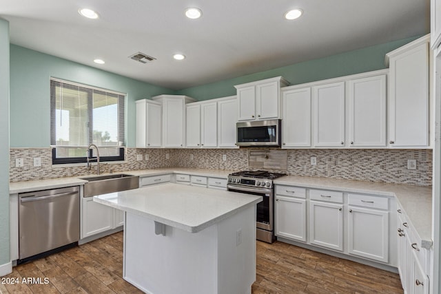 kitchen featuring dark wood-type flooring, white cabinetry, decorative backsplash, and stainless steel appliances