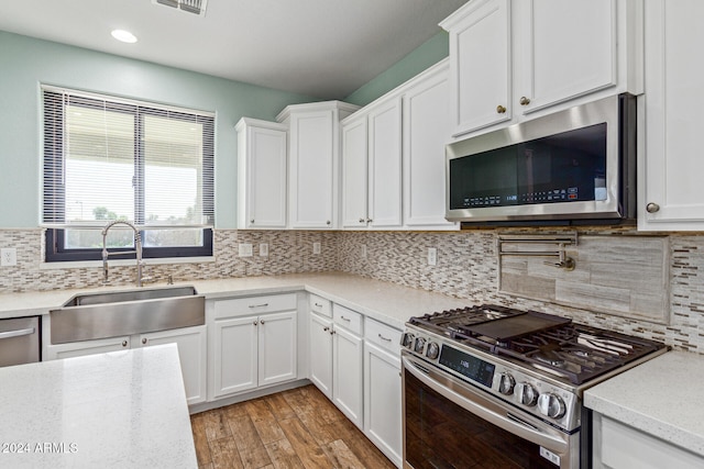 kitchen featuring light hardwood / wood-style flooring, sink, white cabinets, appliances with stainless steel finishes, and tasteful backsplash