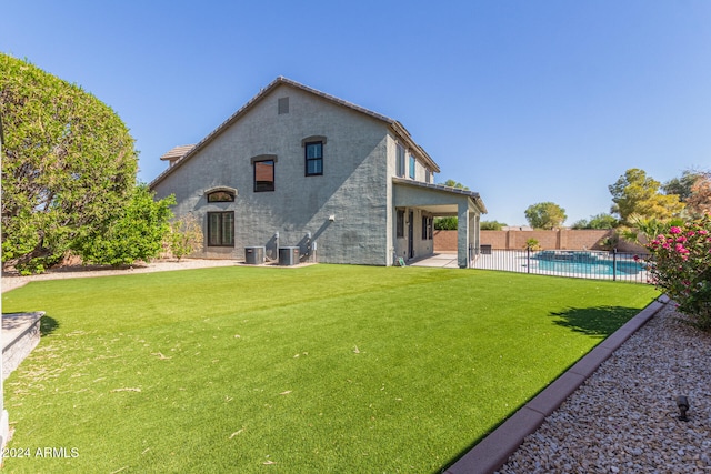 rear view of house featuring a patio area, central AC unit, a lawn, and a fenced in pool