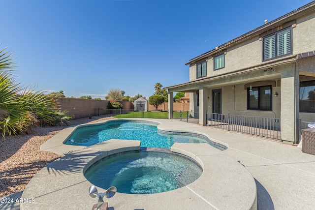 view of pool with an in ground hot tub, a patio area, and a storage shed