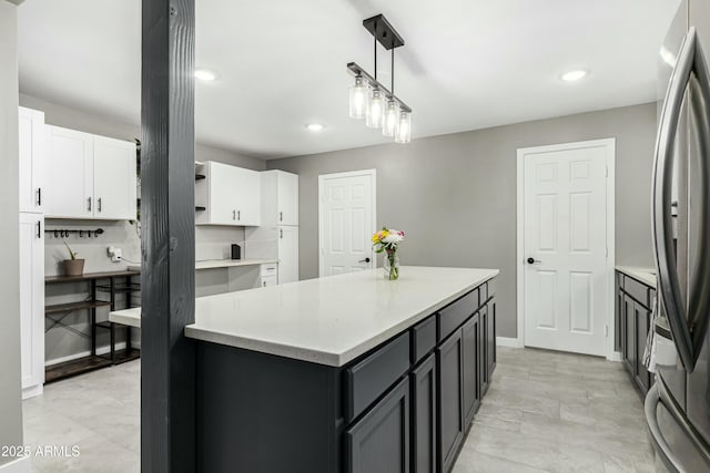 kitchen featuring a center island, decorative light fixtures, white cabinetry, and stainless steel fridge