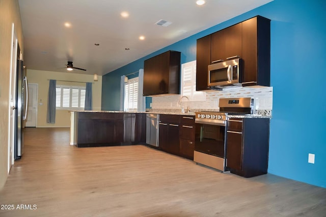 728 S Meadowood Ln, Sierra Vista, AZ 85635 - kitchen with stainless steel appliances, light wood finished floors, a peninsula, a ceiling fan, and tasteful backsplash