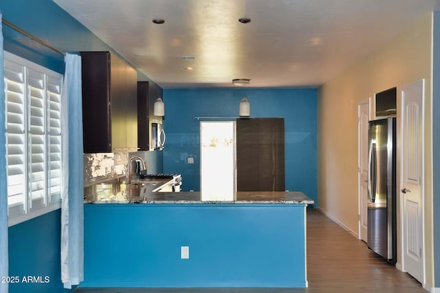 728 S Meadowood Ln, Sierra Vista, AZ 85635 - kitchen featuring appliances with stainless steel finishes, a peninsula, wood finished floors, tasteful backsplash, and baseboards