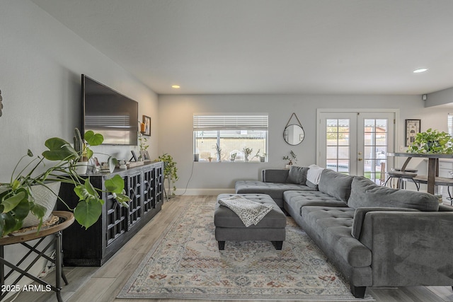 living room featuring french doors, light hardwood / wood-style flooring, and a wealth of natural light