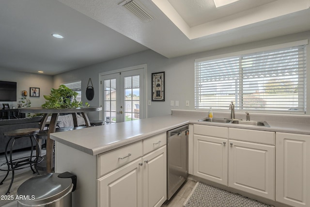 kitchen featuring white cabinetry, stainless steel dishwasher, kitchen peninsula, and sink