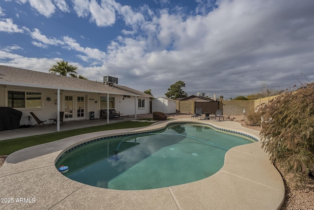 view of swimming pool featuring french doors, a patio, a storage unit, and central air condition unit