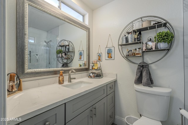 bathroom featuring vanity, a tile shower, and toilet