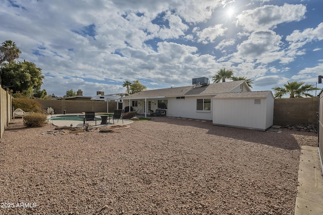 back of property with a shed, a fenced in pool, a patio, and cooling unit